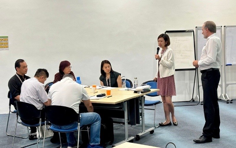 Dr. John Stahl-Wert and woman leading a meeting while she is holding a microphone